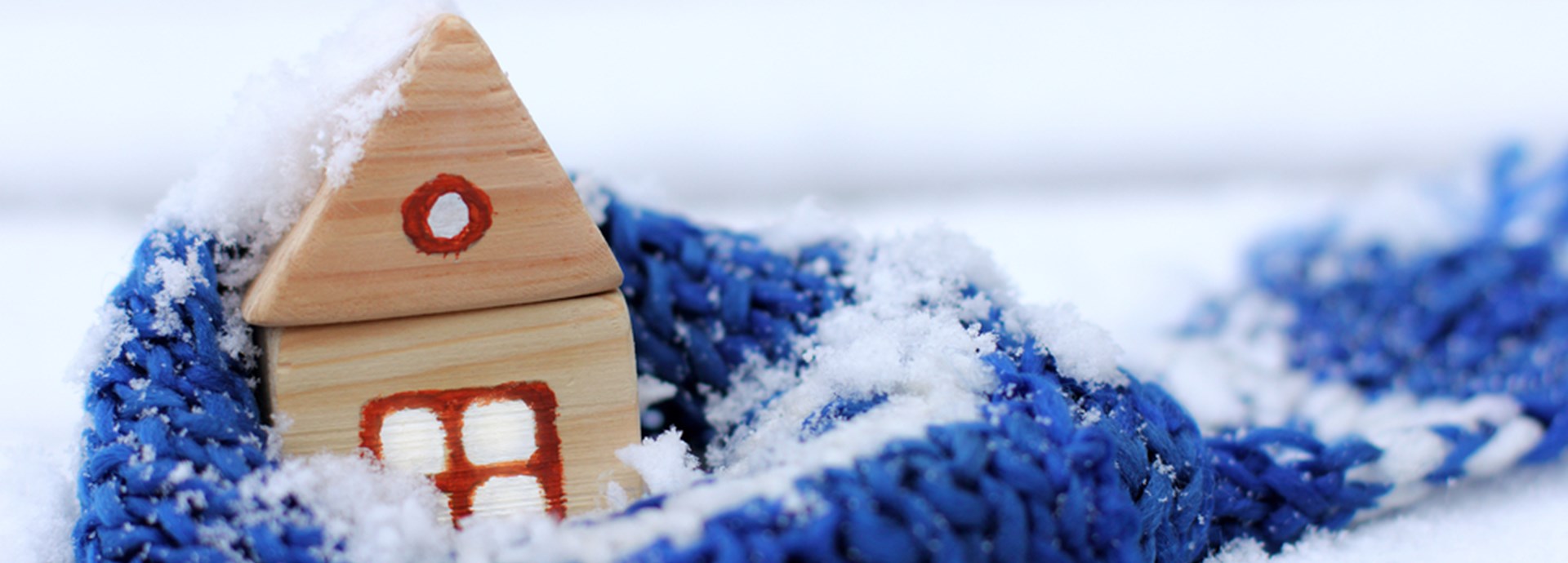 warming blue scarf around a wooden house in the winter season